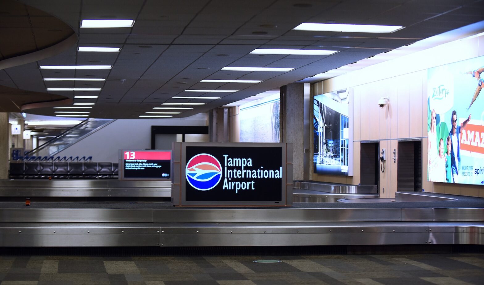 Empty baggage claim area at Tampa International Airport with a sign displaying the airport's name and logo.