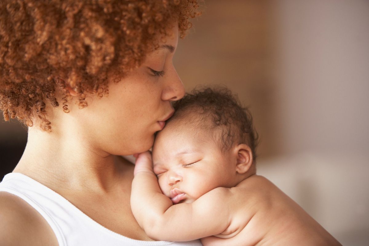 mother kissing a sleeping baby