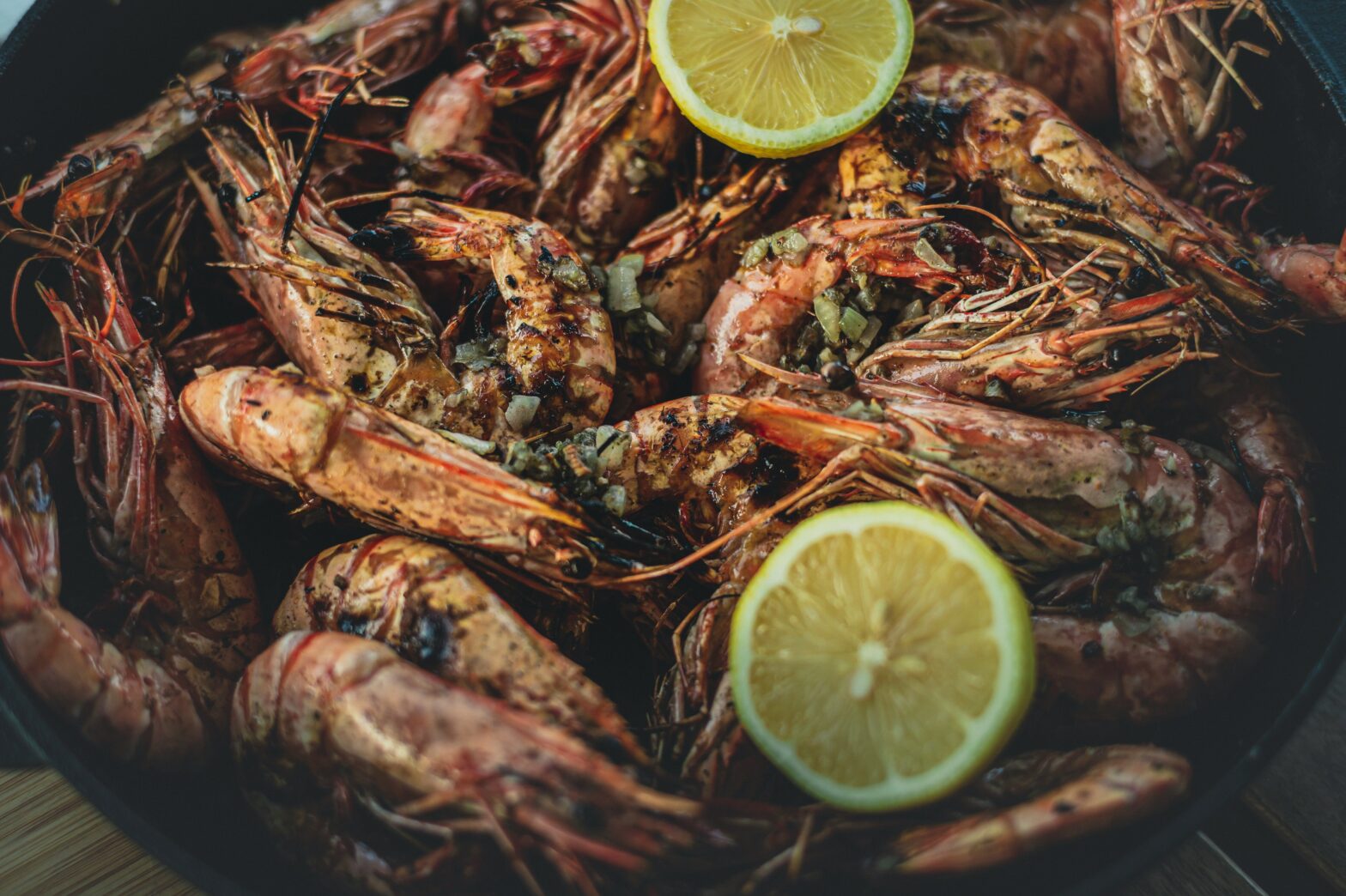 A bunch of boiled shrimp with lemon on top.