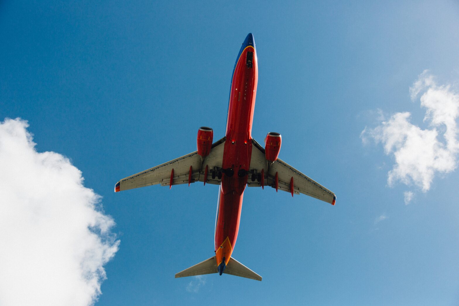 A Southwest airplane in flight during a bright cloudy day.