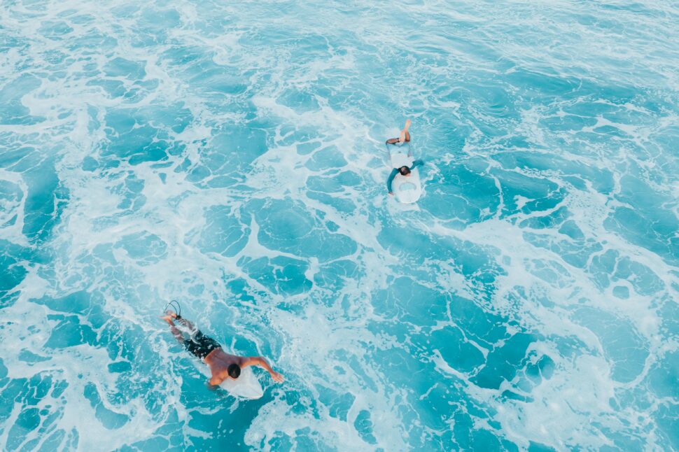 an aerial view of people on surfboards in the water