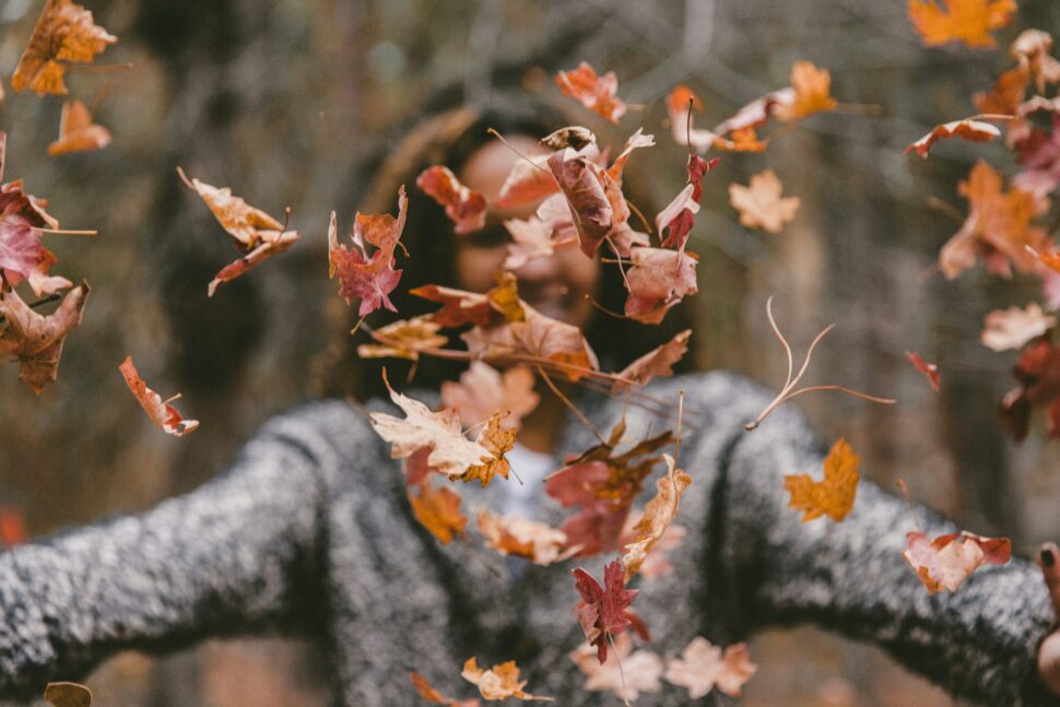 Woman throwing up leaves during Thanksgiving season