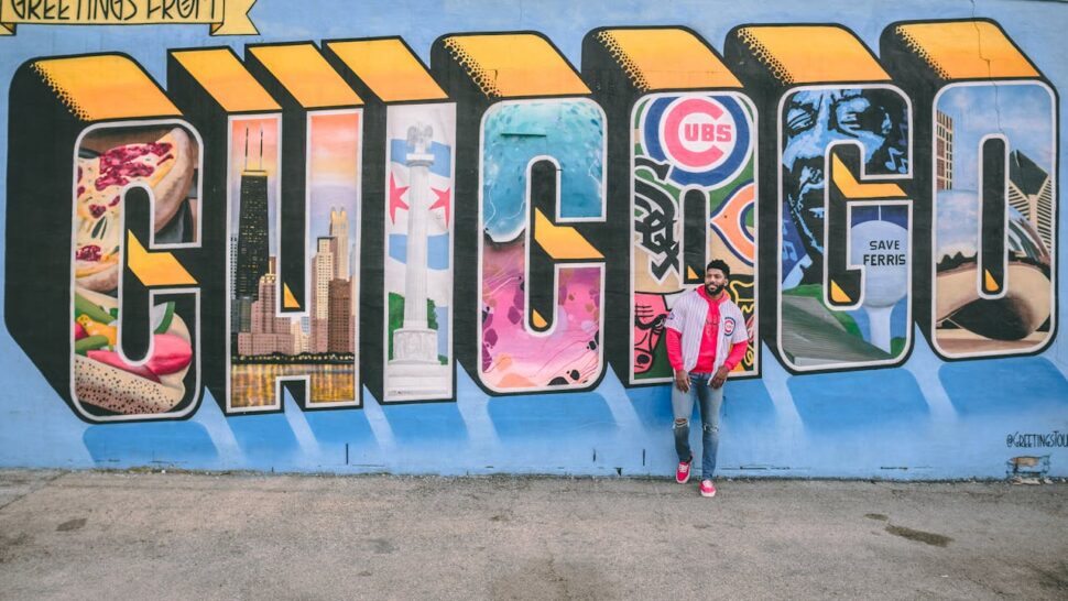 Man posing in Chicago Cubs jersey by Chicago graffiti sign