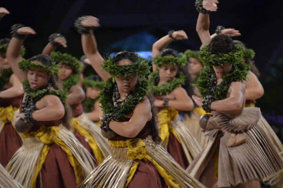 Hula kahiko dancers from Hālau o Kekuhi on stage performing at the Merrie Monarch Festival