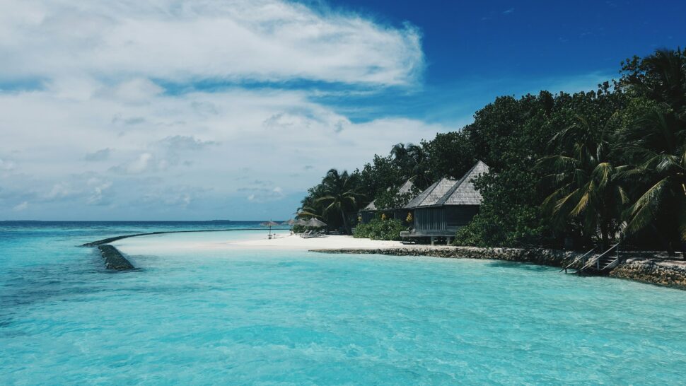 Luxury overwater bungalows in the Maldives surrounded by turquoise blue waters and clear skies.