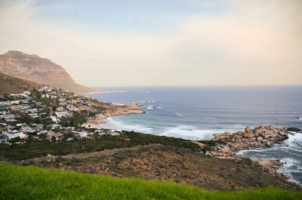 Table Mountain surrounded by lush greenery and vibrant beaches in Cape Town on a sunny day.