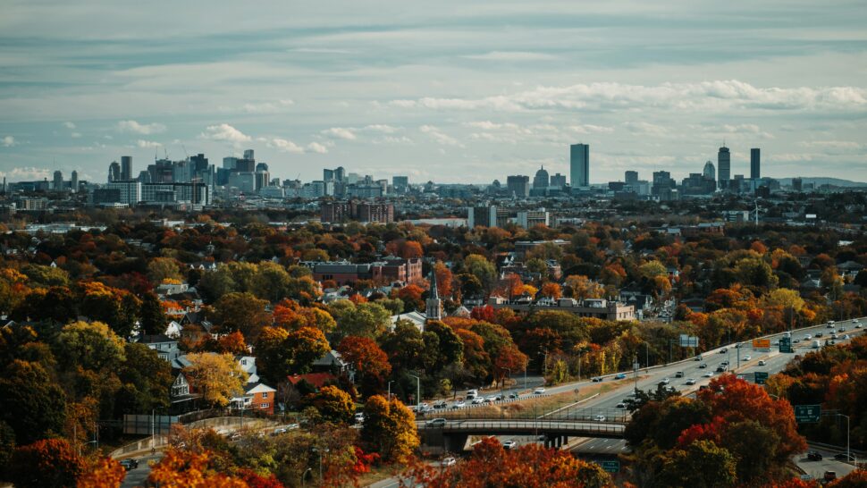 Distant shot of Boston's fall foliage, red brick buildings and open road evoking the city’s rich history