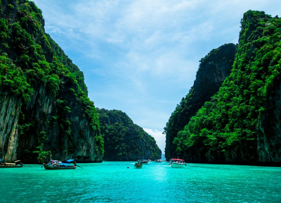 Clear turquoise waters between two lush green cliffs in Phuket, perfect for water activities and sunbathing.