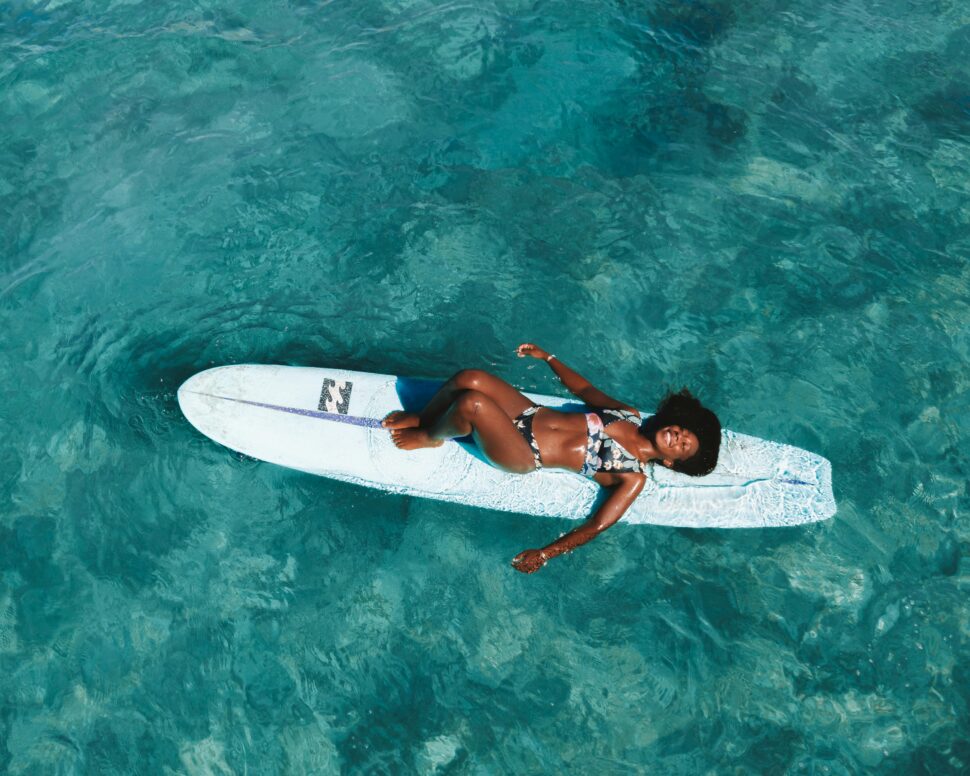 Black woman floating on surfboard