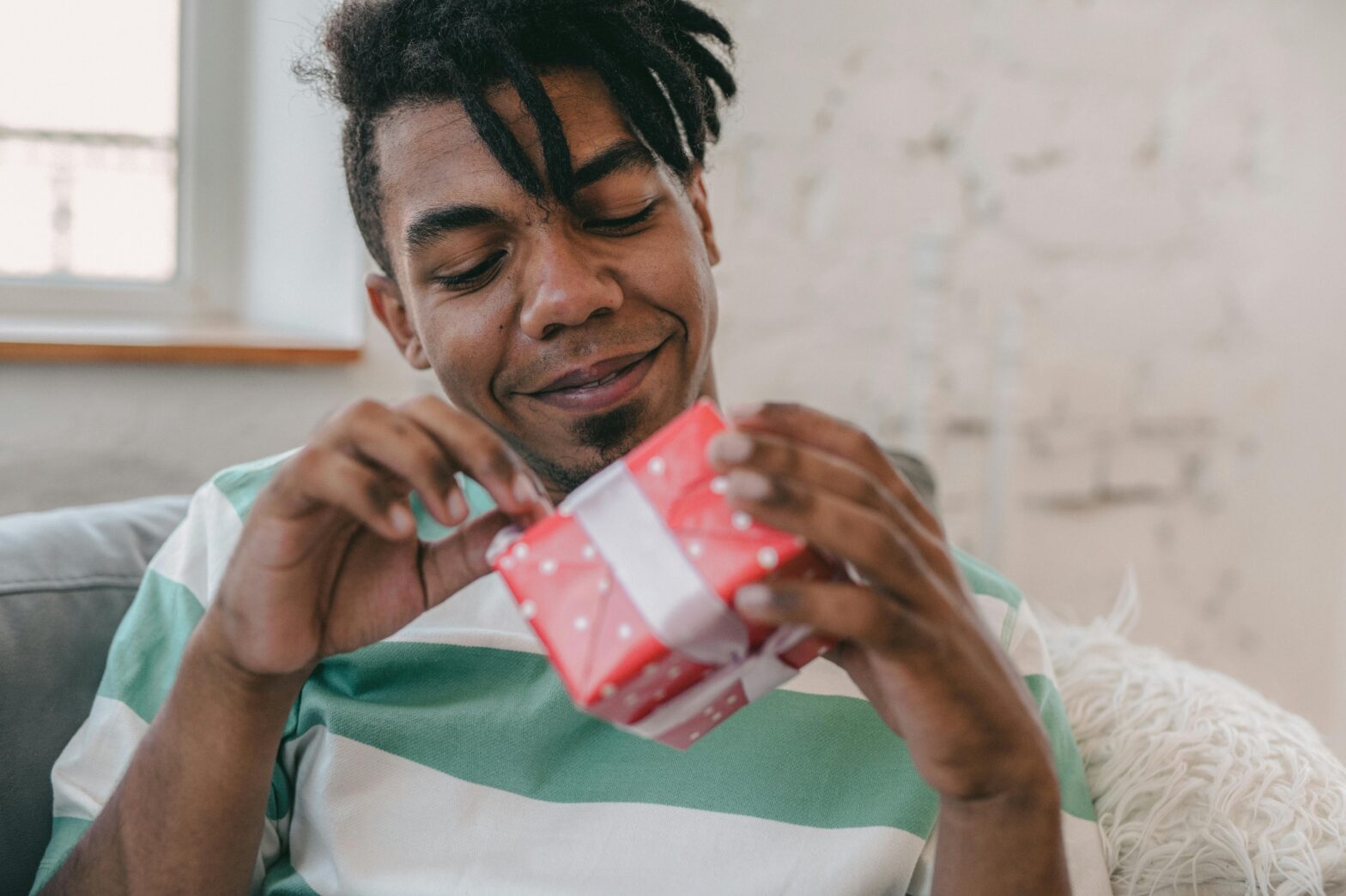 Black man opening a red wrapped gift.