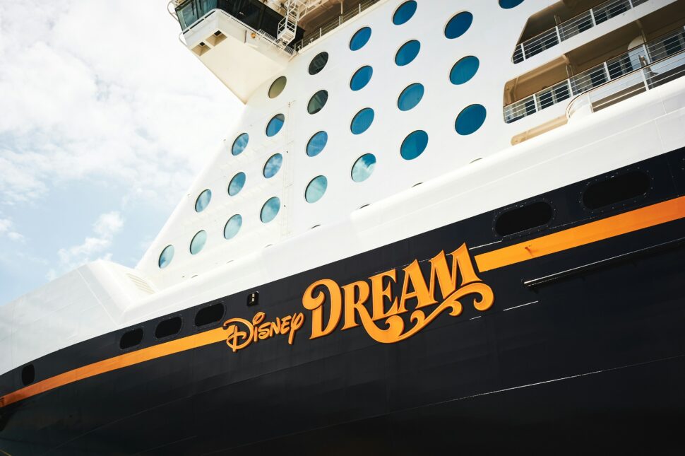 Side view of the Disney Dream cruise ship, showcasing its vibrant exterior, iconic Mickey Mouse emblem, and spacious decks, offering a magical family-friendly experience at sea.