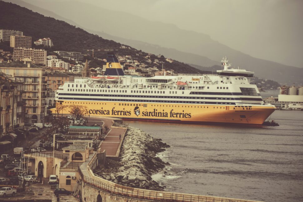 A modern cruise ship docked at a bustling port city during the daytime. 