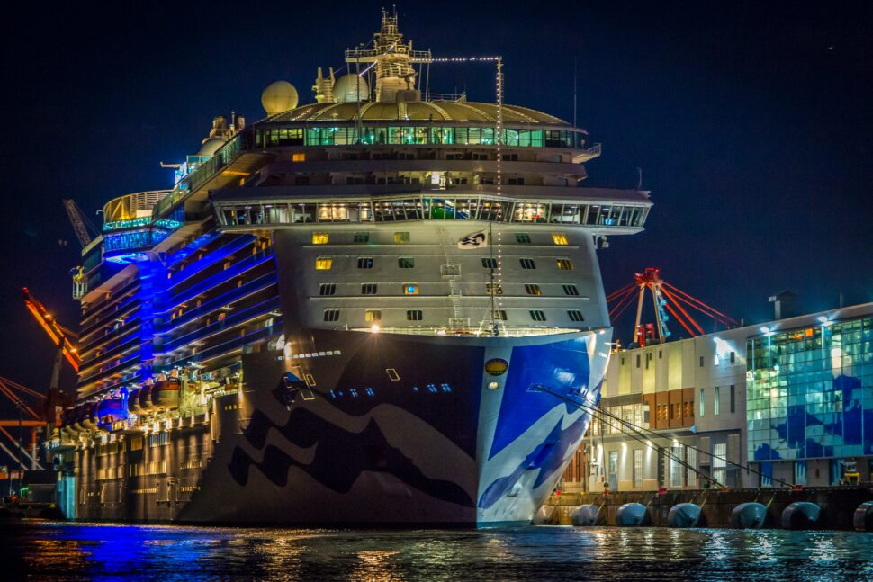 A sleek, modern cruise ship docked at a bustling port city, ready for departure.