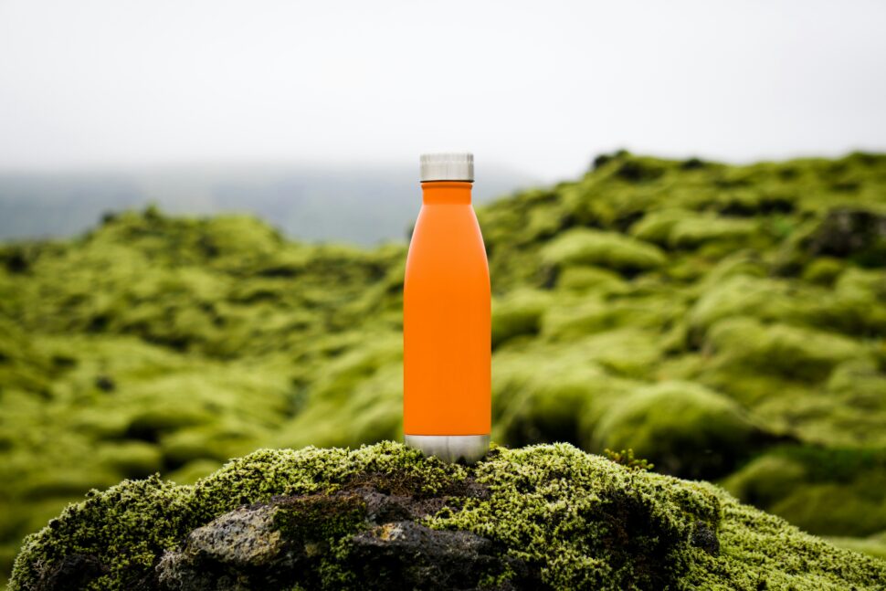 Orange bottle with lush green backdrop before the drop-off for a cliff.