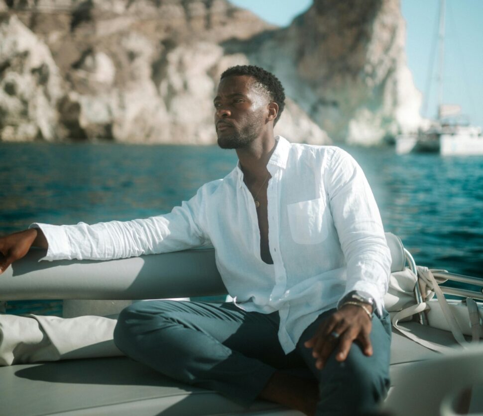 Man in unbuttoned white shirt relaxes on yacht