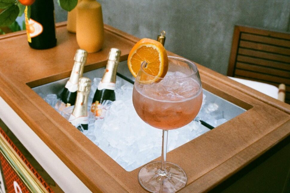 A Cocktail Standing on the Edge of a Counter and Champagne Bottles Cooling in Ice