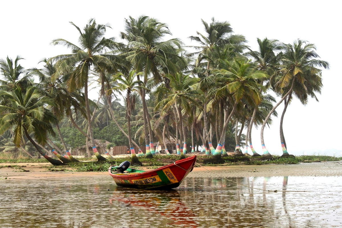 Ada, Ghana with a boat on the water by trees.