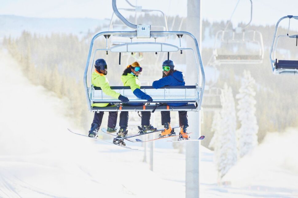 group of male skiers smiling while riding a chairlift