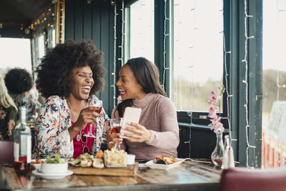 A front view shot of mid-adult women enjoying drinking wine together in a restaurant.