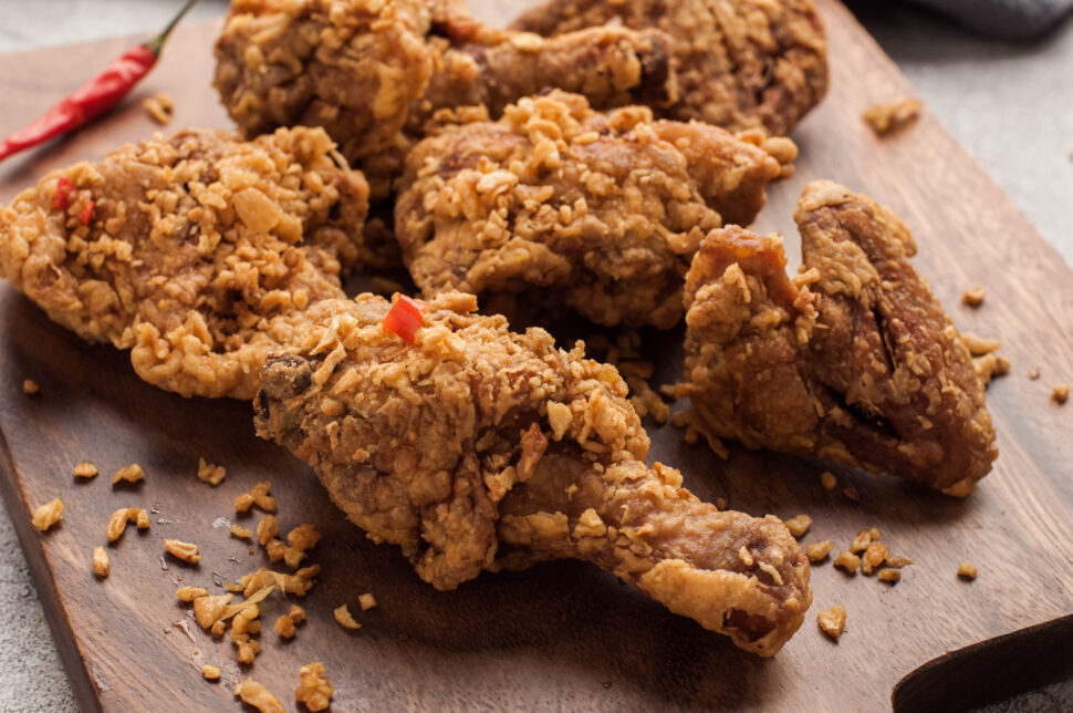 Spicy fried chicken on a cutting board.