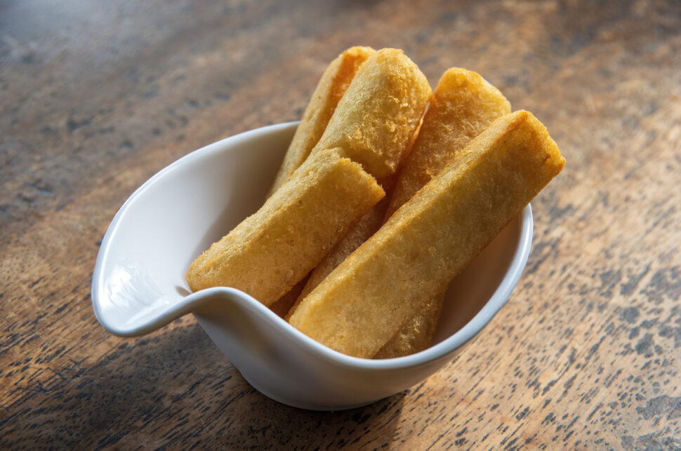 Yuca frita (Yucca/cassava fries) in a white serving bowl on a wooden table top.