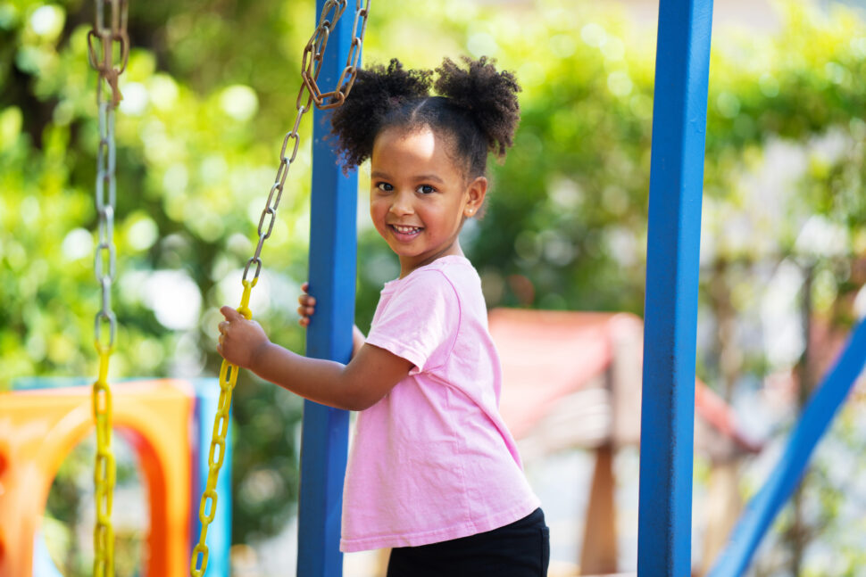 Cute Little girl using a swing on a daycare playground.