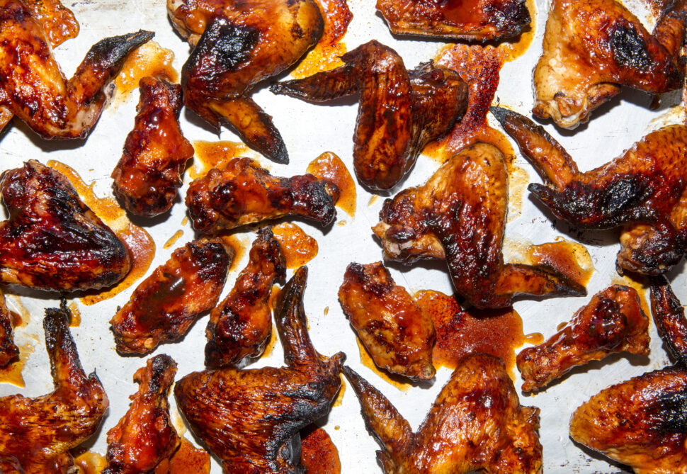 Aerial view of graphic arrangement of bbq chicken wings with sauce and grill marks.