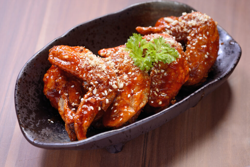 Spicy chicken wings on wooden board.