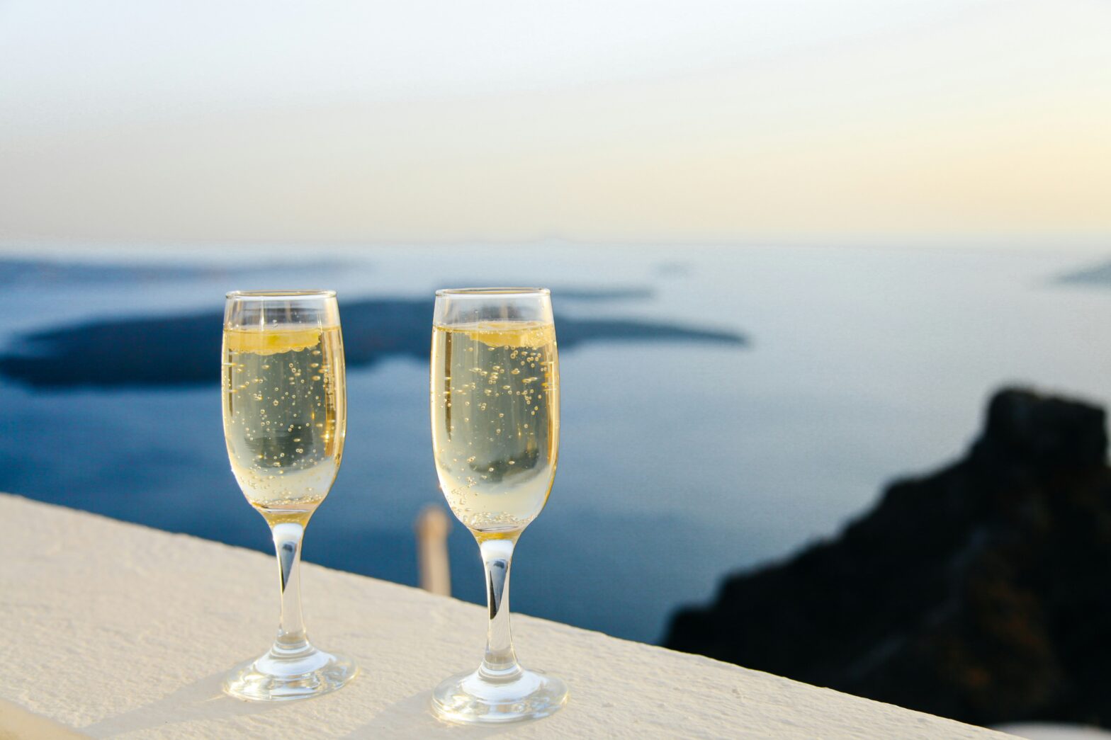 Luxurious champagne glasses in front of water.