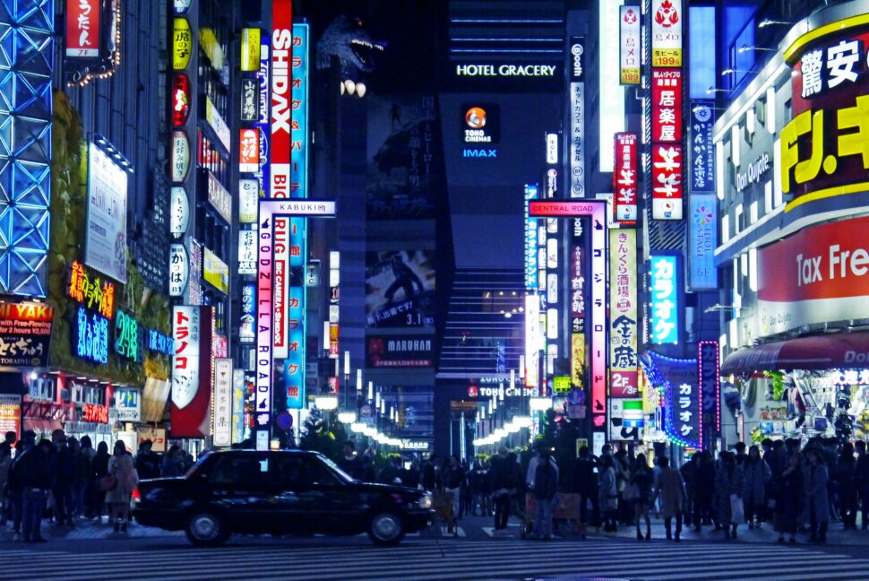 Neon Shinjuku city lights and tourists about the city streets.