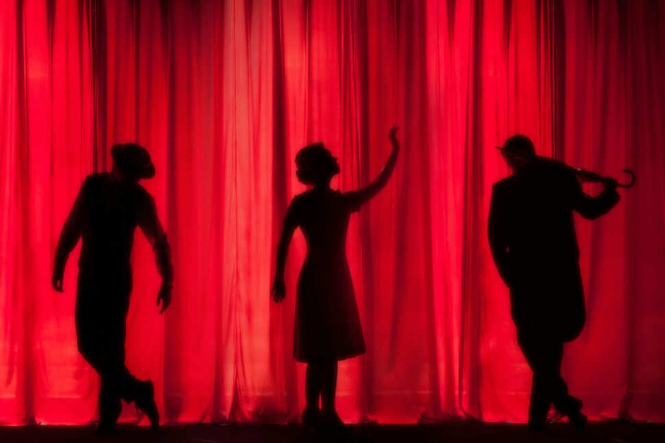 Performers behind the curtain, waiting for the curtain drop, at a theater. 