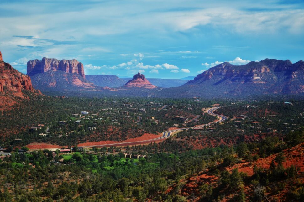 Road cutting through Sedona with distant rock formations in the background. 