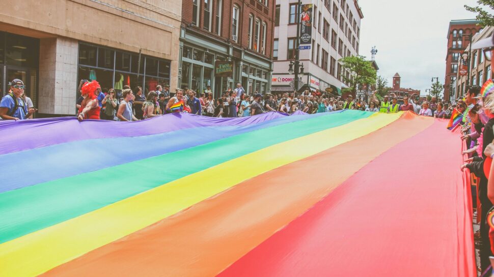 In 2018, Portland, Maine residents carry the large rainbow flag down Congress Street during the annual Pride parade.