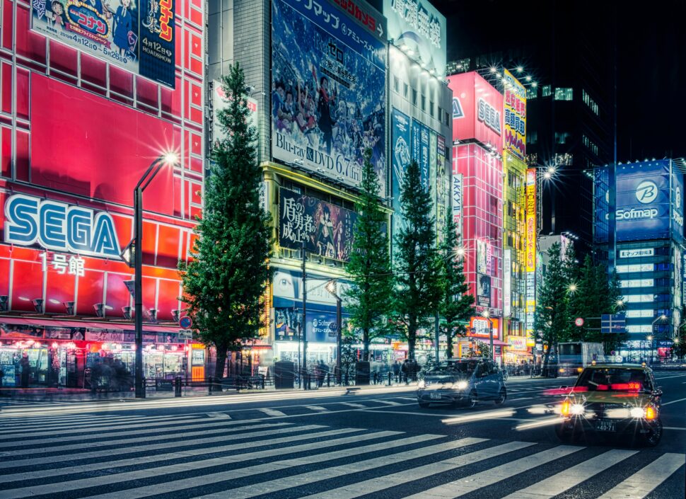 Tokyo shops lit up in neon against a wholesome street.