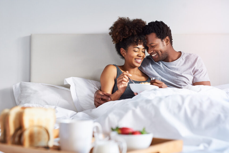 Shot of a happy young couple enjoying breakfast in bed