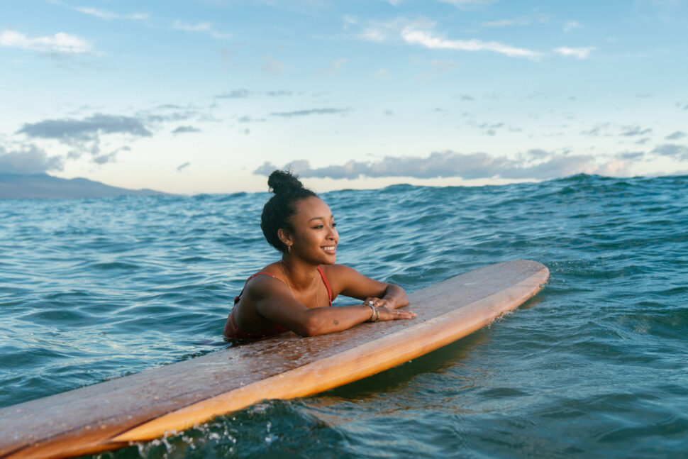 Young woman resting on her surfboard waiting for a wave. 