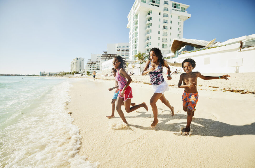 Wide shot of siblings running into ocean while on family vacation