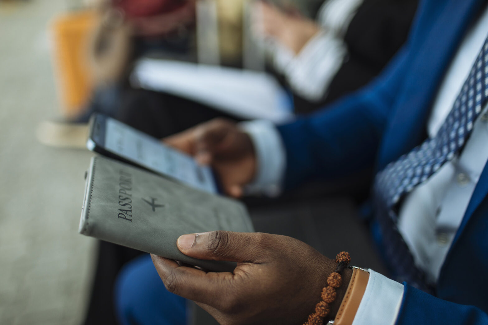 Young businessman in a blue suit holding a passport and sitting at the airport waiting for a flight