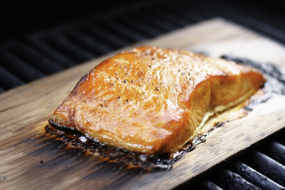 Salmon fillet with coarse ground pepper, grilled over a cedar plank.