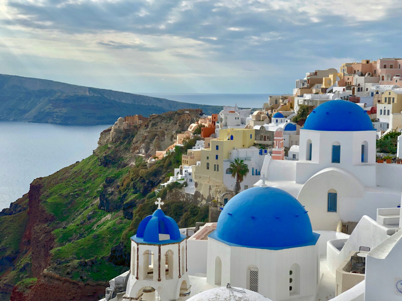 cliffside view of the whitewashed stone buildings and blue-domed churches overlooking the Aegean Sea in Santorini, Greece