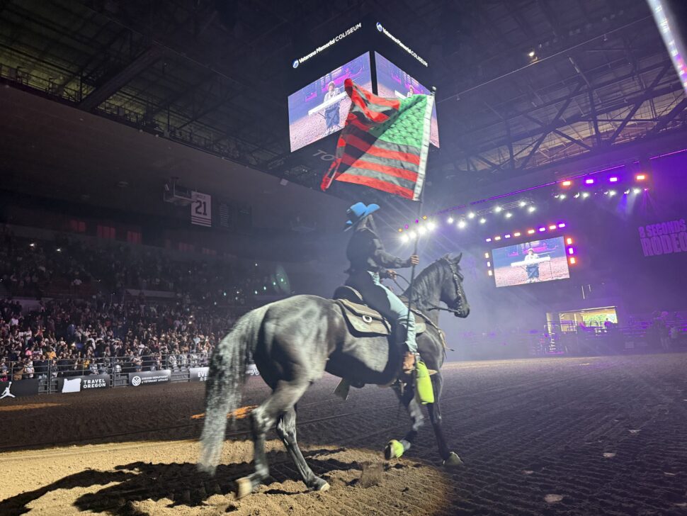 Kourtnee Solomon rides on Black horse with Pan African Flag during 8 Seconds Rodeo in Portland, Oregon