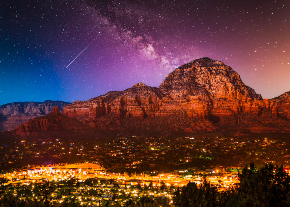 Milky Way Galaxy stars over Sedona Arizona landscape with city lights.