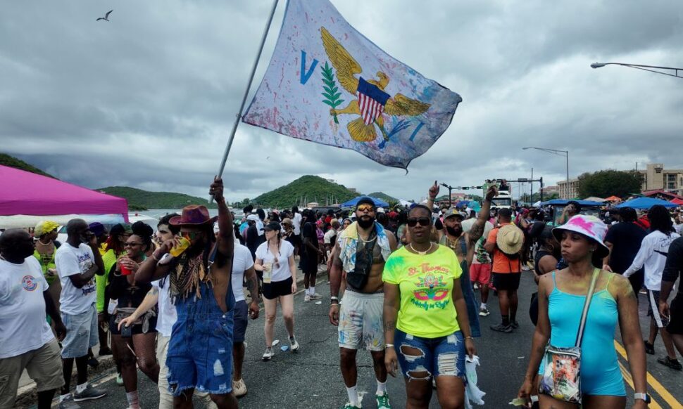 man waving USVI flag in crowd during St. Thomas Carnival 2025