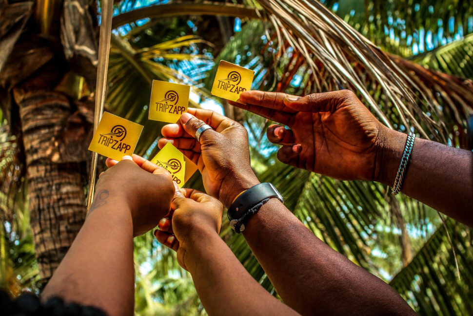 several hands holding TripZapp logo stickers