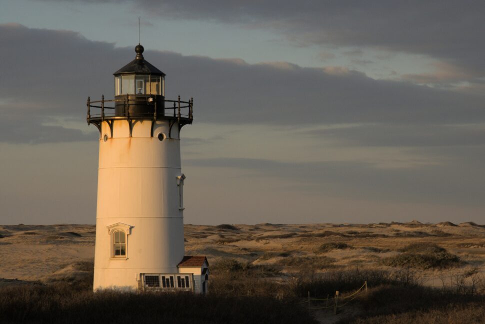 A White Lighthouse on a Grassy Field
